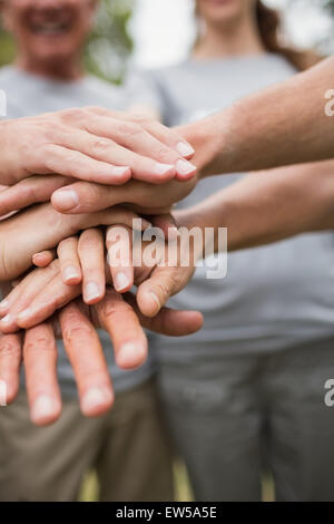 Felice famiglia di volontariato di mettere le loro mani insieme Foto Stock