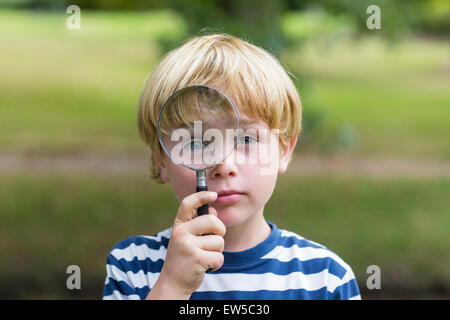 Curioso ragazzino guardando attraverso la lente di ingrandimento Foto Stock