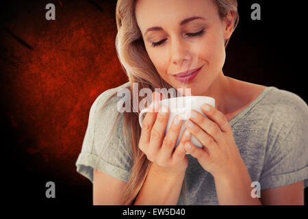 Immagine composita della bionda sorridente con bevanda calda rilassante Foto Stock