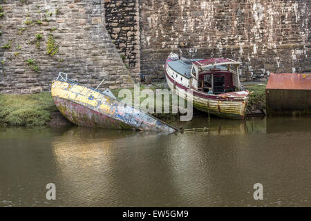 Una metà sunken piccola barca sul fiume Conwy un altra barca in appoggio sulle banche del fiume. Foto Stock