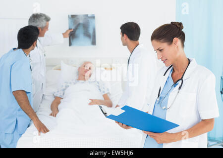 La lettura dei report con i colleghi e il paziente dietro Foto Stock