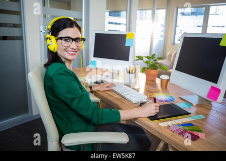 Sorridente brunette lavorando alla sua scrivania e ascolto di musica Foto Stock