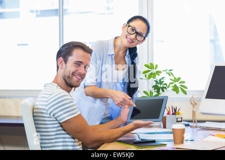 Partner sorridente lavorando insieme su tablet Foto Stock