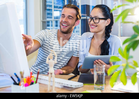 Partner sorridente lavorando insieme su tablet e computer Foto Stock