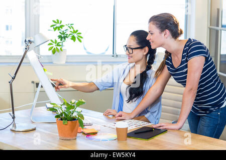 Partner sorridente lavorando insieme con le fotografie sul computer Foto Stock