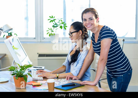 Partner sorridente lavorando insieme sul computer Foto Stock