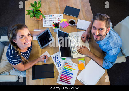 Sorridente partner di lavoro al banco tramite laptop e tablet Foto Stock