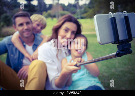 La famiglia felice nel parco tenendo selfie Foto Stock