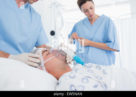 I medici tenendo le maschere di ossigeno e di esame di gocciolamento endovenoso Foto Stock