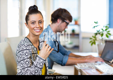 Imprenditrice sorridente in posa con il suo partner dietro Foto Stock