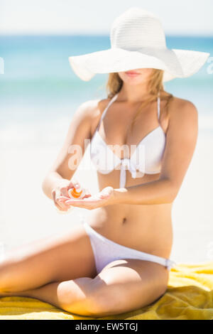 Bella donna bionda messa sun tan lotion sulla sua mano Foto Stock