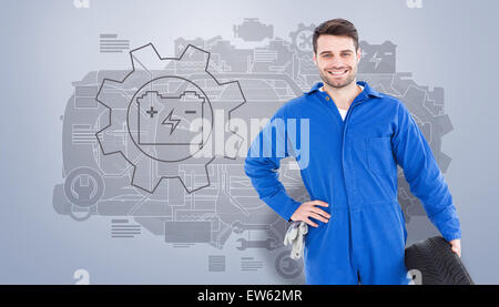 Immagine composita di sorridere meccanico maschio di contenimento del pneumatico Foto Stock