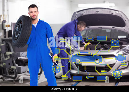 Immagine composita di sorridere meccanico maschio di contenimento del pneumatico Foto Stock