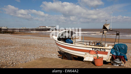 Una barca da pesca a Cromer Beach, Norfolk, Inghilterra, Regno Unito, con il mare e pier in background Foto Stock