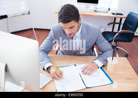 Imprenditore seduti a tavola e firma il documento di Office Foto Stock