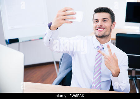 Happy businessman seduti a tavola e facendo selfie foto sullo smartphone in office Foto Stock