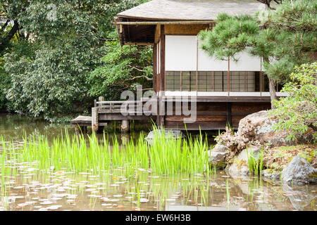 Il Giardino di Shosei-en, Kyoto, la teahouse di Sochin-kyo. Primo piano è lo stagno e gigli d'acqua che crescono in primavera, con la casa del tè in background. Foto Stock