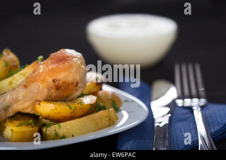 Patate al forno con pollo arrosto coscia sulla piastra bianca Foto Stock