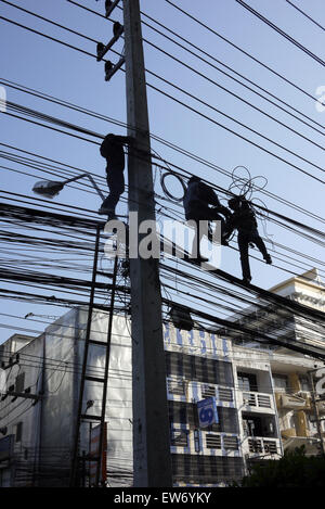 Cavo elettrico i montatori che lavorano in una situazione di pericolo al di sopra di una strada di città in Pattaya Thailandia Foto Stock