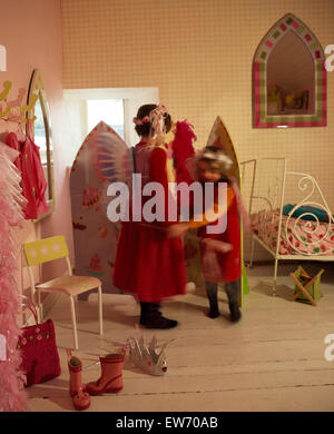 Due piccole bambine vestirsi in una economia camera da letto di stile Foto Stock