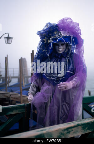 Un Reveller indossando maschera tradizionale e accappatoi presso il Carnevale di Venezia per solo uso editoriale Foto Stock