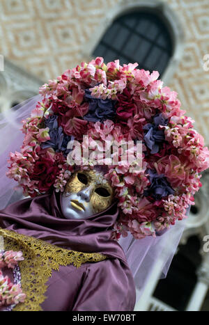 Un Reveller indossando maschera tradizionale e accappatoi presso il Carnevale di Venezia per solo uso editoriale Foto Stock