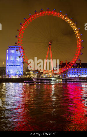 Visualizzare attraverso il Fiume Tamigi del London Eye illuminata di notte Foto Stock
