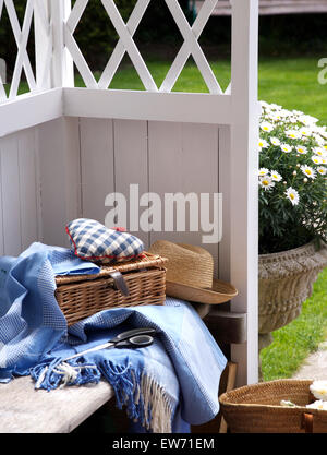 In vimini cesto da picnic con tessuto blu cuore e Blu orlata rug sul sedile all'interno di un bianco gazebo in legno Foto Stock