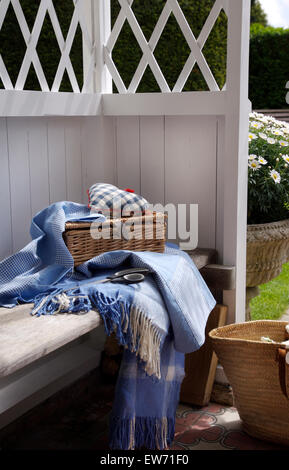 In vimini cesto da picnic e Blu orlata rug sul sedile interno e bianco gazebo in legno Foto Stock