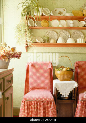 Rosa copre allentato su sedie vintage sotto la Cina su scaffali di pino in colore verde pallido degli anni ottanta sala da pranzo Foto Stock