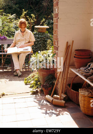 Donna seduta e la lettura sulla panchina da giardino Foto Stock