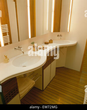 Specchi illuminati al di sopra di lavabi in curva ripiano vanity in stile anni trenta anni ottanta bagno Foto Stock