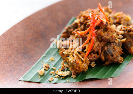 Carni bovine indonesiano rendang guarnito con patatine fritte lo scalogno e peperoncino rosso. Foto Stock