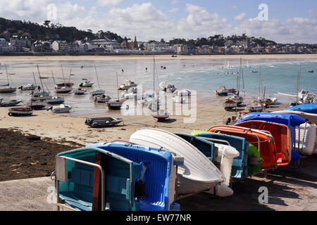 Barche a vela a marea di declino sulla spiaggia e le piccole barche a remi in banchina Foto Stock