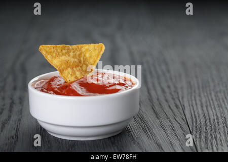 Tortilla chip nella ciotola con la salsa di pomodoro sulla tavola di legno Foto Stock