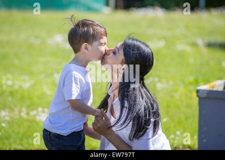 Madre baciare il suo piccolo figlio Foto Stock