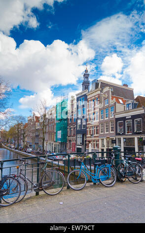 Biciclette su un ponte di amsterdam con alcune case monumentali in background Foto Stock