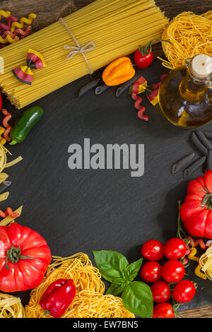 La pasta grezza con ingridients sulla lavagna nera Foto Stock