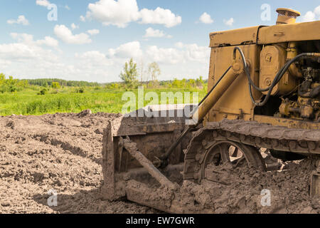 Close-up di fango Caterpillar coperto le tracce di un giallo terra industriale escavatore Macchina Foto Stock