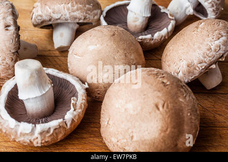 Big marrone di funghi champignon sparsi sul tagliere di legno in pianura e capovolto Foto Stock