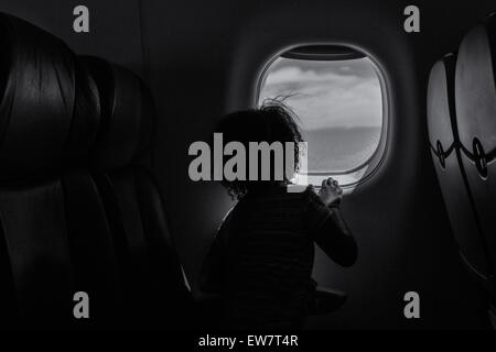 Vista posteriore di una ragazza guardando fuori della finestra su un piano Foto Stock