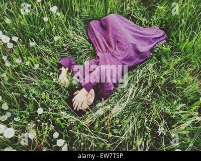 Vista in elevazione di una donna sdraiata in erba con la mano che copre il volto Foto Stock