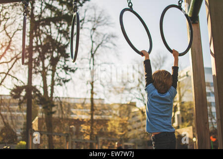 Ragazzo che pende da anelli al parco giochi, Stati Uniti Foto Stock