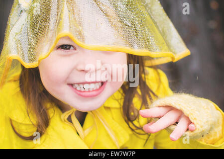 Ragazza sorridente che indossa cappotto e cappello giallo Foto Stock