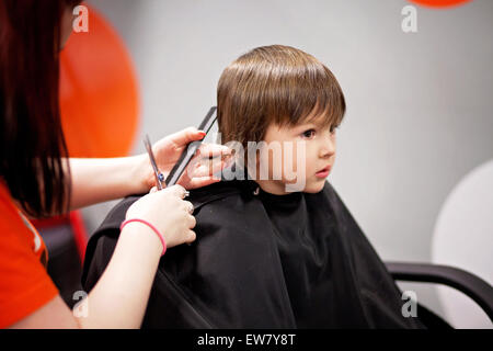 Carino piccolo ragazzo, avente taglio di capelli in un barbiere Foto Stock