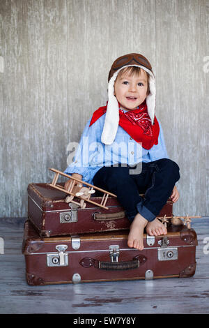 Little Boy, giocando con piani in legno, indoor, seduto su una valigia Foto Stock