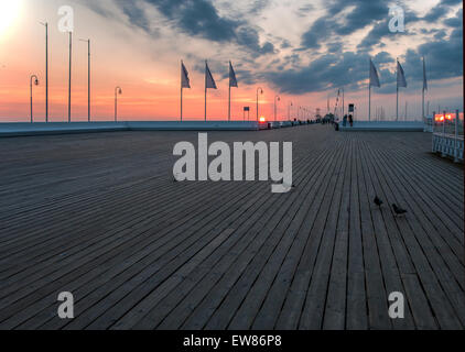 Sunrise al molo in legno (molo) in Sopot, Polonia, con persone e piccioni Foto Stock