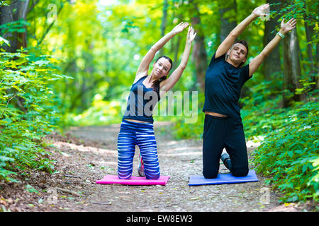 Giovani attiva giovane facendo stretching esercizi yoga al di fuori in posizione di parcheggio Foto Stock