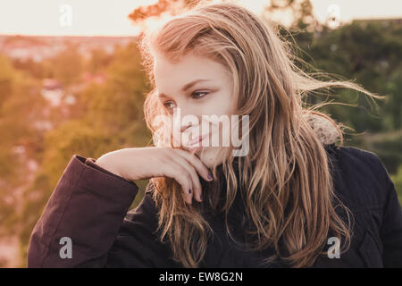 Outdoor closeup ritratto di sorridente caucasico teenage ragazza bionda con serata brillante luce solare LUCE POSTERIORE Foto Stock