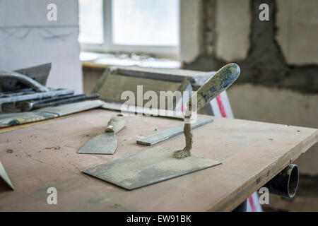 Strumenti di un stuccatore/mason durante la sua pausa su un tavolo in un sito in costruzione Foto Stock